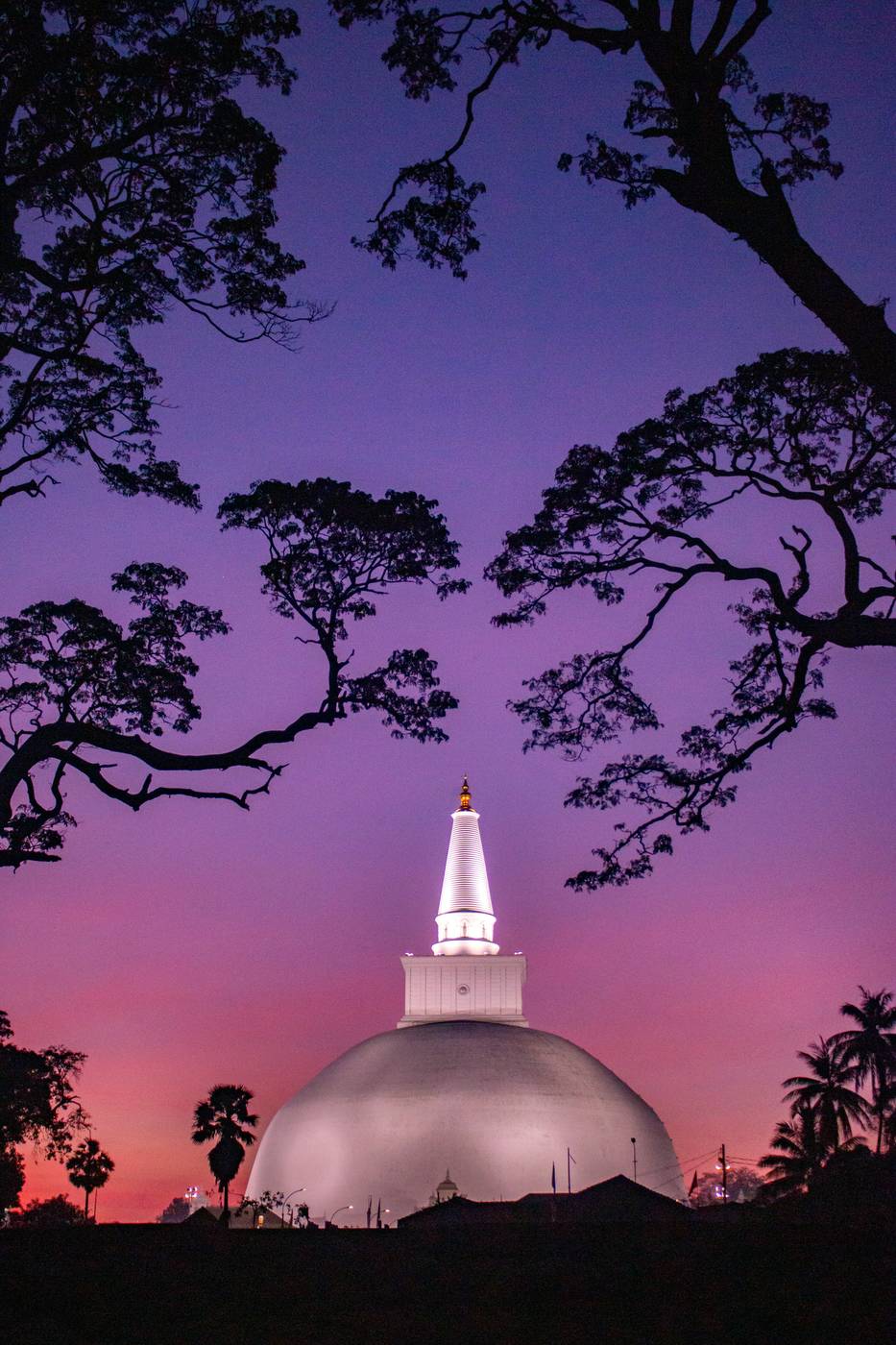Ancient stupa silhouetted against a pink sunset sky in Anuradhapura
