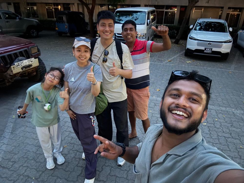 A guide and a group of travellers posing together by their van