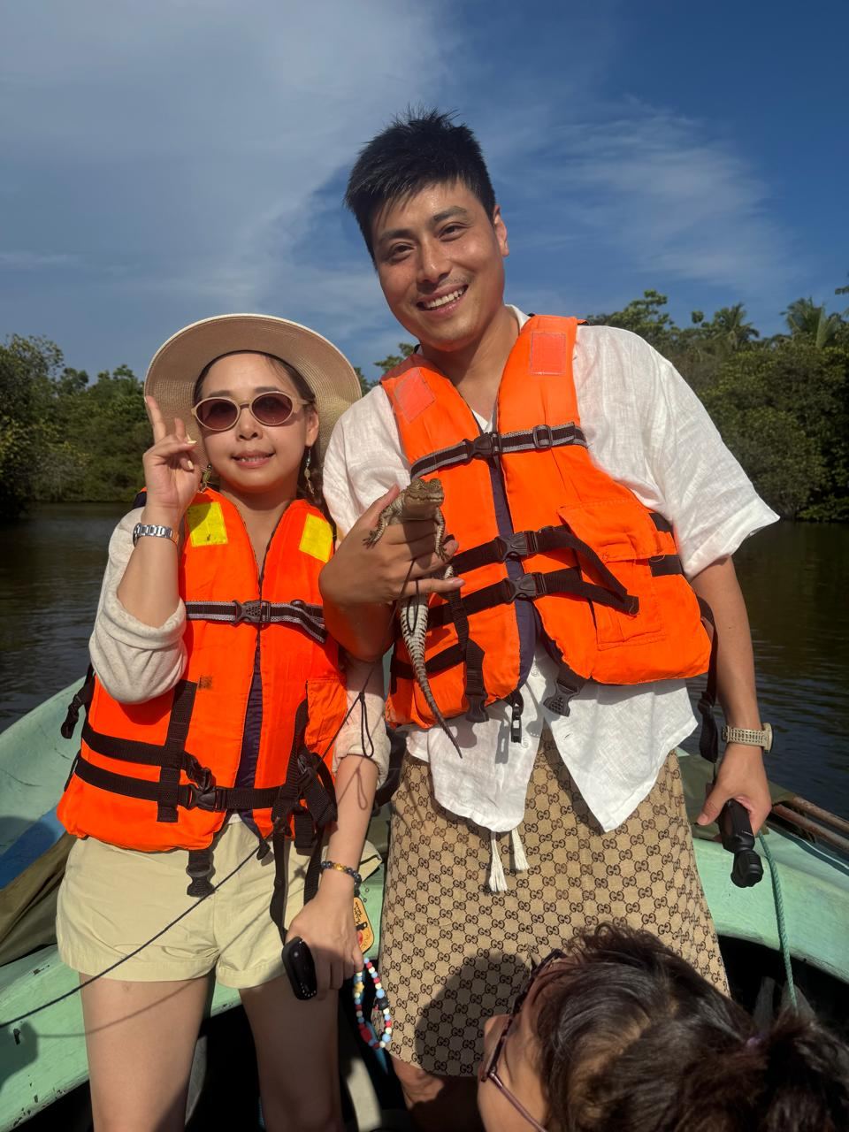 Two travellers holding a small monitor lizard on a mangrove boat trip