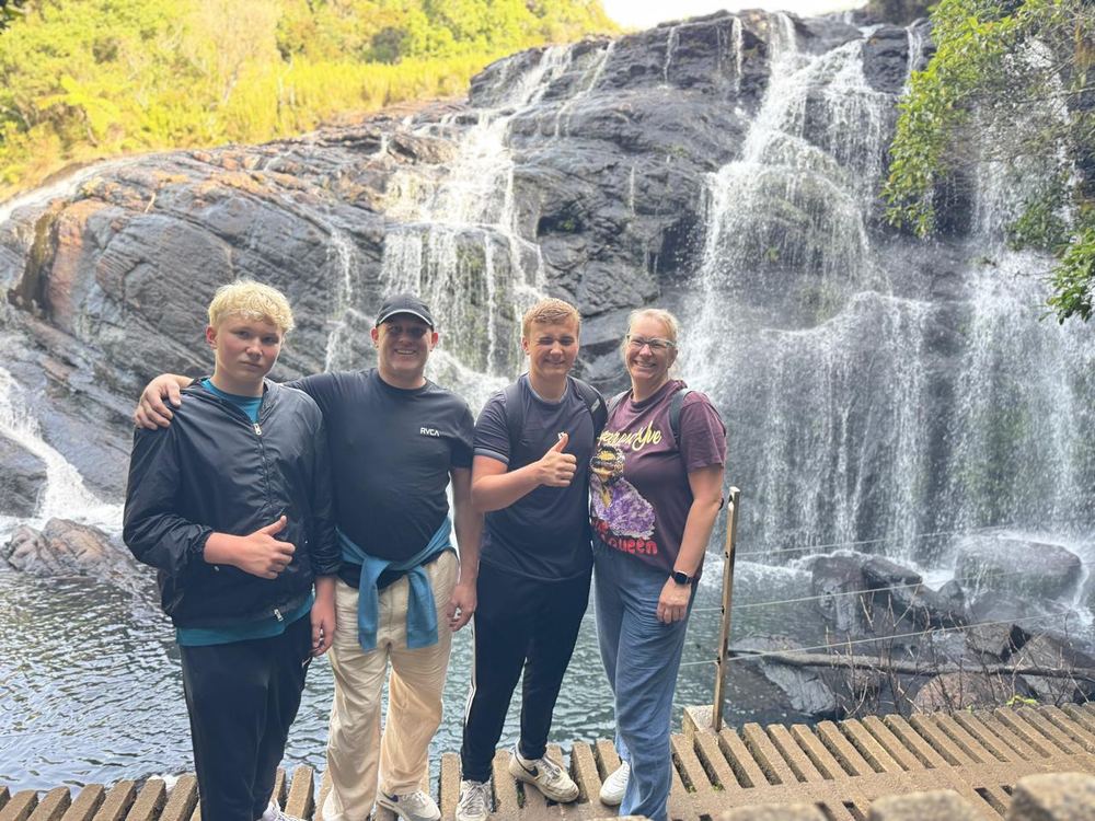 A family posing in front of a hill-country waterfall